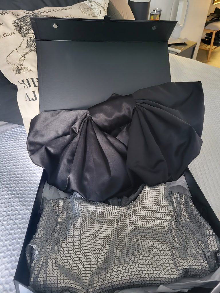 Ophelia-inspired sequin birthday dress with satin bow folded neatly in gift box after arriving in New Zealand.