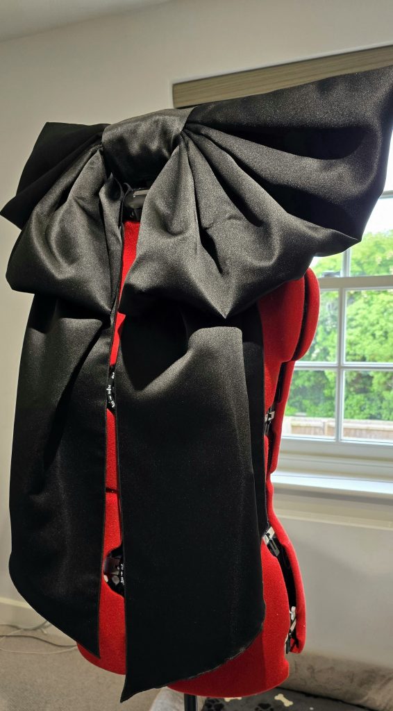 Handmade oversized satin bow for Ophelia-inspired birthday dress, crafted in matte fabric with structured folds.